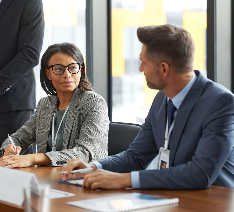 Two professionals discussing papers at a board meeting