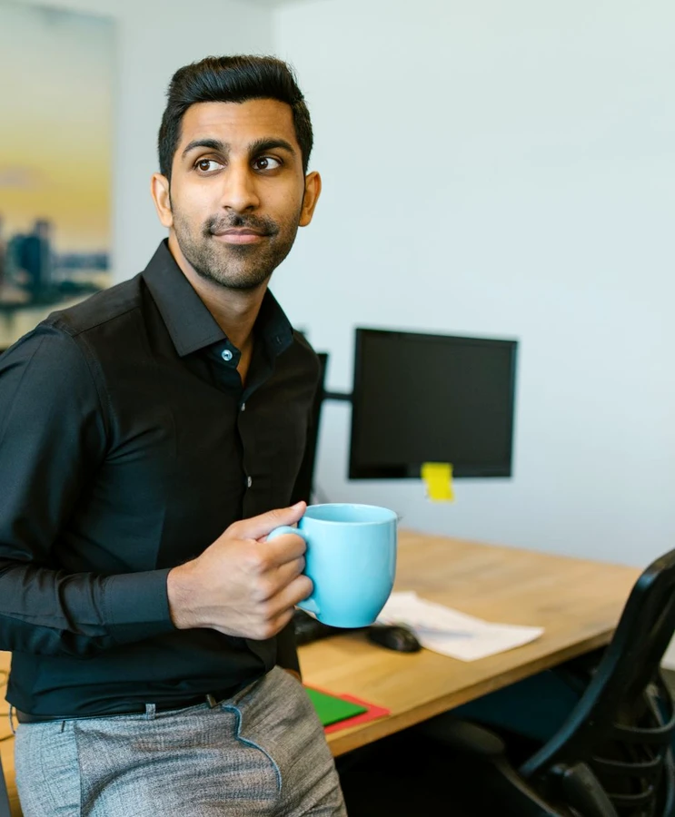 A man holding a coffee cup in a modern office