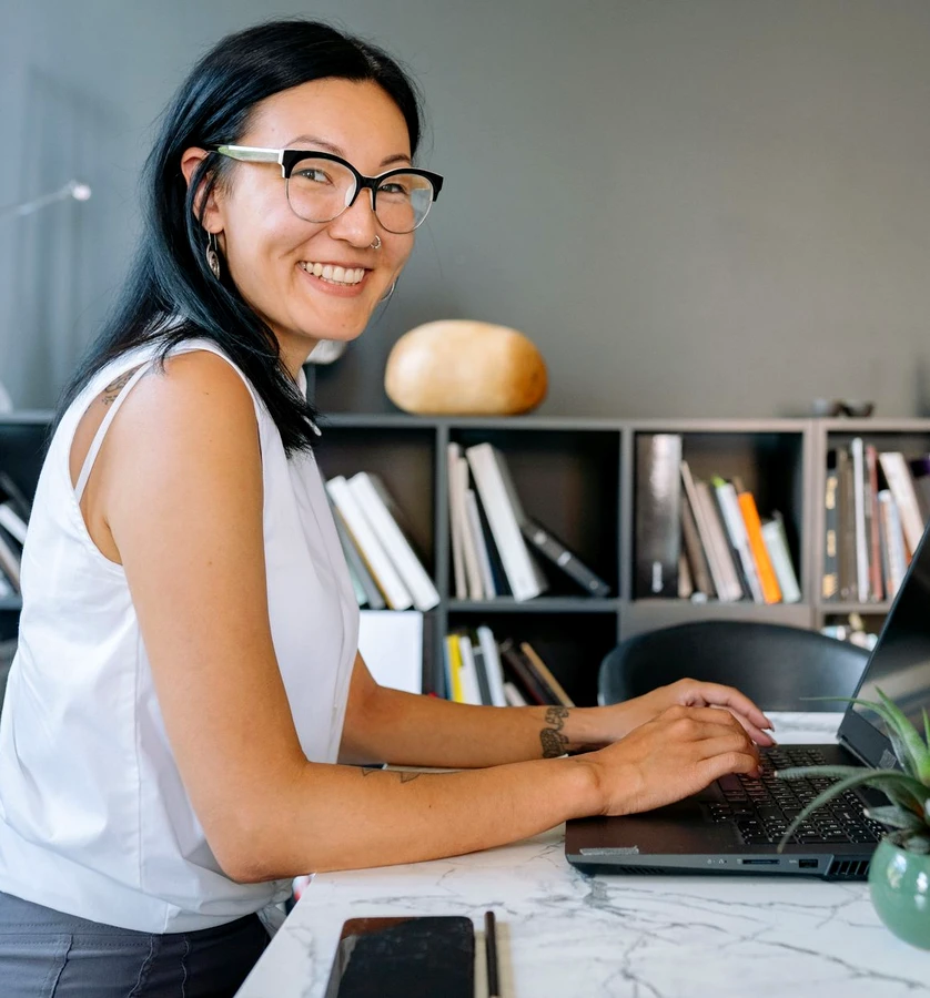 A smiling woman working on a laptop