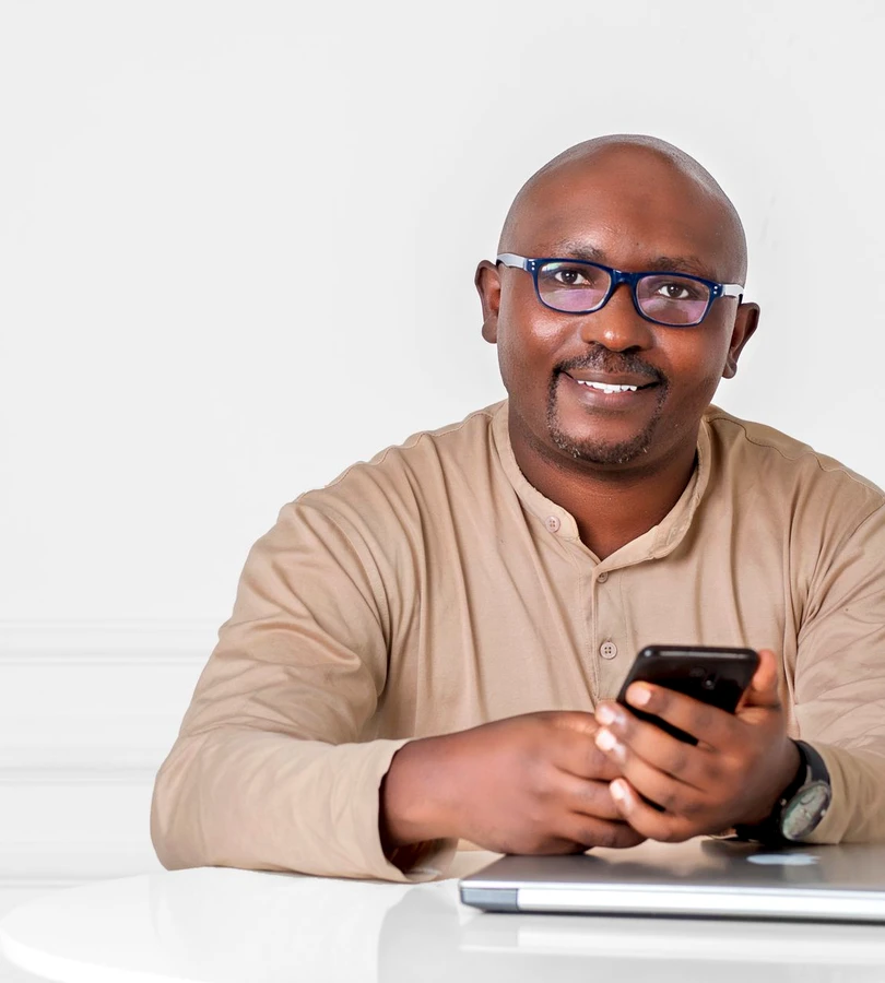 A smiling man holding a phone at a table