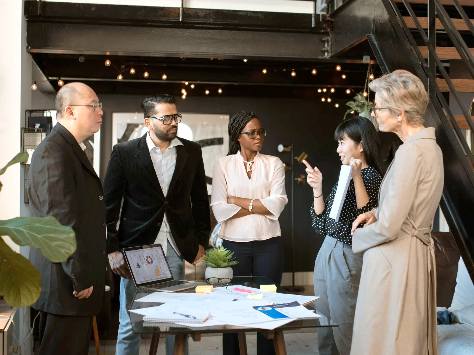 Five colleagues talking around a table in a bright two-storey office
